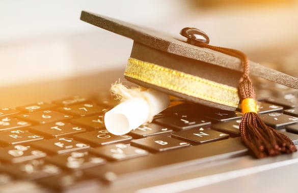 Chapéu de graduação sobre diploma e teclado de computador, simbolizando uma graduação semipresencial