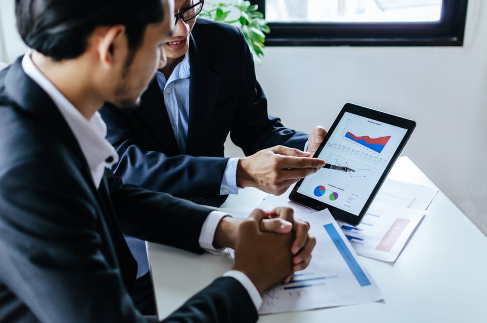 Profissionais de Administração com gráficos em papéis e tablets